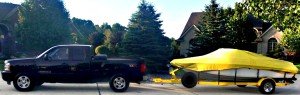 boat with a yellow cover being pulled behind a black truck