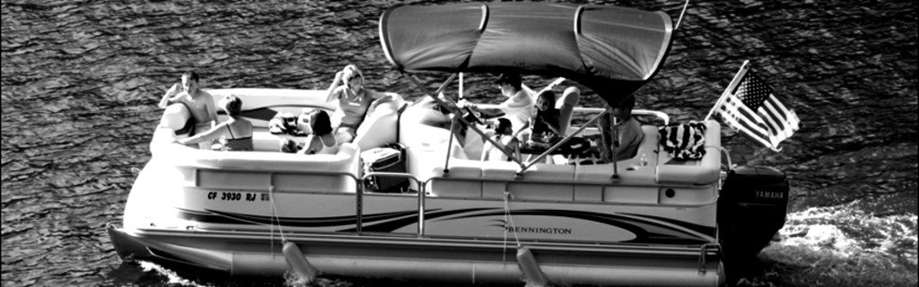 black and white photo of a pontoon boat on lake