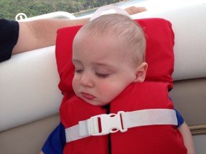child with a life jacket on asleep in the boat