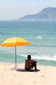 man sitting under a beach umbrella beside the water