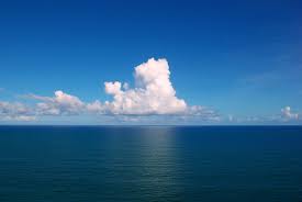 beautiful picture of a deep blue sea with bright blue sky and white puffy clouds