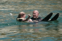 man and little girl in water learning to water ski