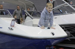 Cute Kid wearing Hoodie in Bow of Boat at Boat Show with Family